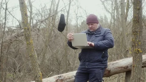 Freelancer in nature typing with his left hand on a laptop while sitting on Vídeos de archivo 170983283