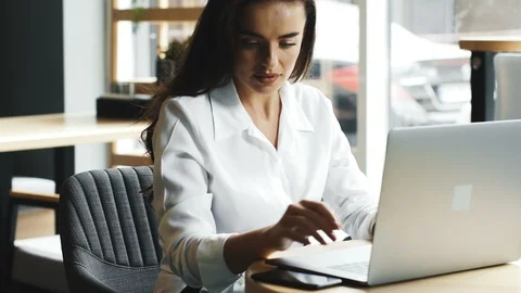 Freelancer picking up the phone call in the modern interior cafe with computer Stock Footage 117130480