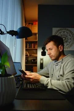 Freelancer procrastinating at home office, scrolling phone instead of working Stock Photos