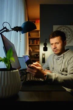 Freelancer procrastinating at home office, scrolling phone instead of working Stock Photos