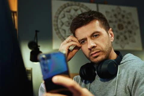 Freelancer procrastinating at home office, scrolling phone instead of working Stock Photos