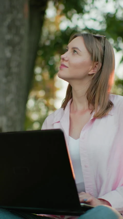 Freelancer Seated on Grass Working on Laptop with Thoughtful Smile and Natural Stock Footage 317583449