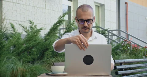 Freelancer sits at table putting on glasses for eyes protect Stock Footage 255208386