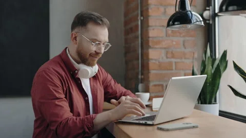 Freelancer sitting at the cafe and typing something at the laptop with smile. Stock Footage 176846421