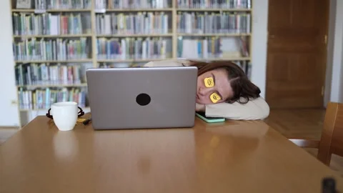 Freelancer sleeps at laptop with funny sticky notes covering her eyes 스톡 동영상 342178448