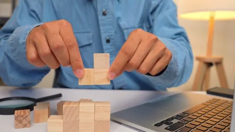 A freelancer stacking wooden blocks beside a laptop represents growth. Stock Footage 316568130