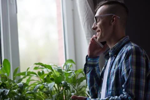 Freelancer talking on phone standing by the window. Stock Photos