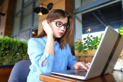 Freelancer talking by smartphone and working with laptop at cafe Foto stock