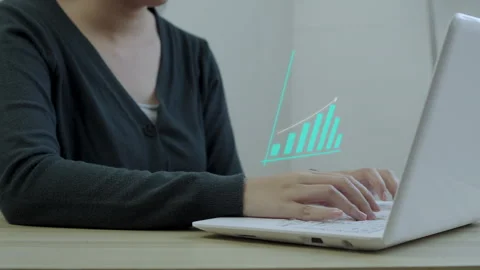 Freelancer typing on laptop with digital bar chart graphic depicting sales Stock Footage 345091863
