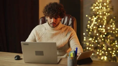 Freelancer using laptop and digital table on Christmas. Focused young man Stock Footage 231286974