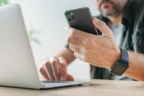Freelancer using laptop computer and mobile smart phone at the same time, mul Stock Photos