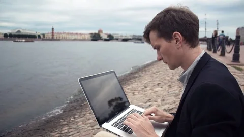 Freelancer using laptop sitting on bench near seafront. Summer day Video stock 80009135