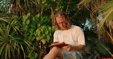 A freelancer using a tablet computer by the ocean near the tropical jungle Stock Footage 105734538