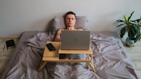 Freelancer wakes up suddenly in bed and resumes work, urgent project deadline Video stock 314893008