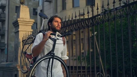 Freelancer walking down the street and carries his bike slow motion Stock Footage 79238966