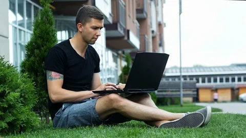 Freelancer work on laptop in the open air while sitting on grass Stock Footage 113740710