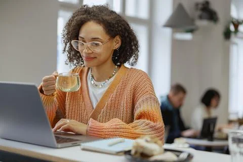 A freelancer worker uses a laptop on a table with a cup of coffee Stock Photos