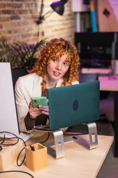 Freelancer working at her desk using laptop and smartphone Stock Photos