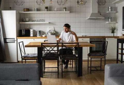 Freelancer working from home sitting on a kitchen worktop and using laptop Stock Photos