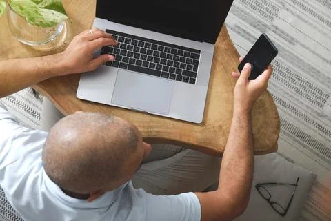 Freelancer working from home using laptop and smartphone Stock Photos