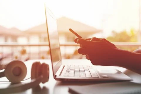 A freelancer working on laptop computer and holding smart phone working from Stock Photos