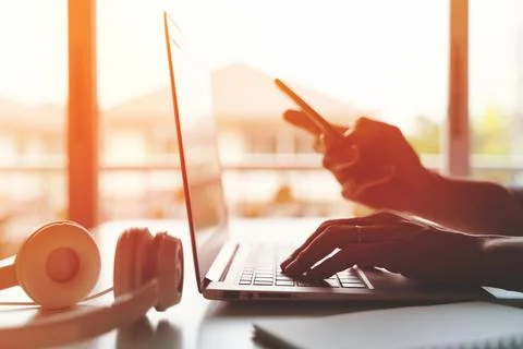 A freelancer working on laptop computer and holding smart phone working from Stock Photos