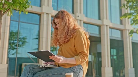 Freelancer working on laptop in front of office center building. Young woman Stock Footage 316467080