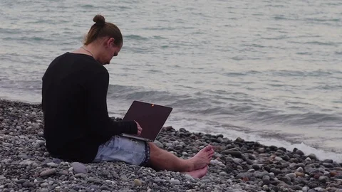 Freelancer working with a laptop on the seashore Stock Footage 100749158