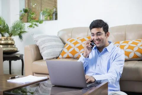 Freelancer Working On Laptop While Talking On Phone Stock Photos