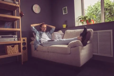 Freelancer working on project lying on sofa at home. Stock Photos