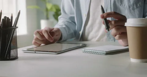 Freelancer working at a tablet computer at home, browsing through web pages Video stock 136374311