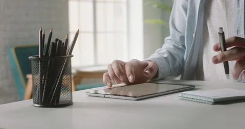 Freelancer working at a tablet computer at home, browsing through web pages Stock-Footage 137350005