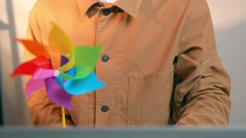A freelancer works on a laptop while holding a vibrant pinwheel. Stock Footage 317600459