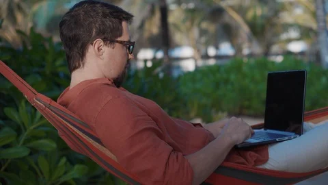 Freelancer works remotely by notebook, lying in hammock Stock Footage 127566571