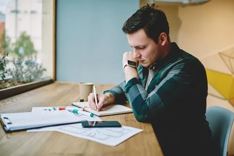 Freelancer writing in notepad in cafeteria Stock Photos