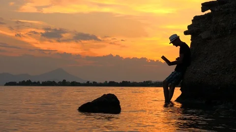 Freelancing guy working near the rocks and the sea. Business man on vacation in Stock Footage 116163383