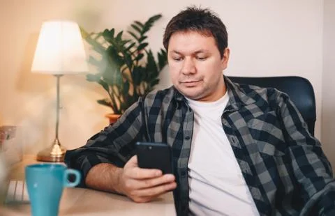 Freelancing young man focused while typing on his mobile phone, sitting in a  Stock Photos