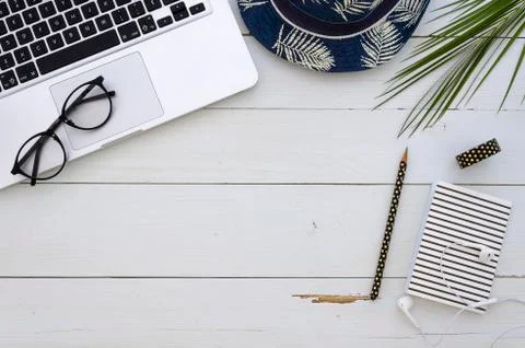 Freelencer workspace with silver notebook, hat, palm leaf,glasses and office Stock Photos