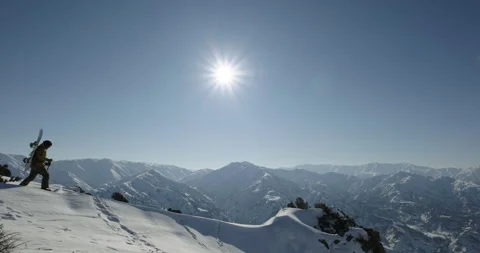 Freeride snowboarder walking in deep snow to the mountain peak to ride downhill Stock Footage 256106644