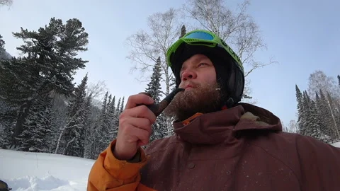 Freerider with a beard smokes a real pipe in the winter forest Stock Footage 98962901