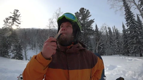 Freerider with a beard smokes a real pipe in the winter forest Stock Footage 98962963