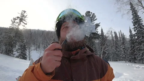 Freerider with a beard smokes a real pipe in the winter forest Stock Footage 98963033