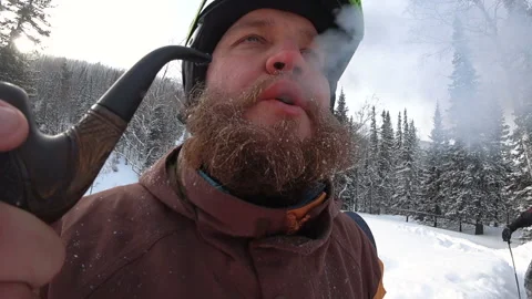 Freerider with a beard smokes a real pipe in the winter forest Stock Footage 98963052