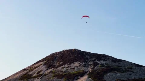 Freestyle paraglider soars over Great Sugar Loaf with plane contrail in sky Stock Footage 311637887