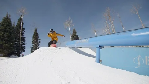 Freestyle snowboarder performing tail slide on a rail Stock Footage 113199376