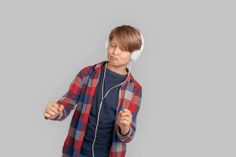 Freestyle. Young boy in headphones standing isolated on grey dancing smiling Stock Photos
