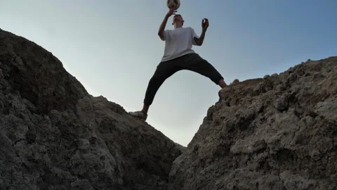 Freestyler balancing a ball on his head among the rocks Stock Footage 133520357