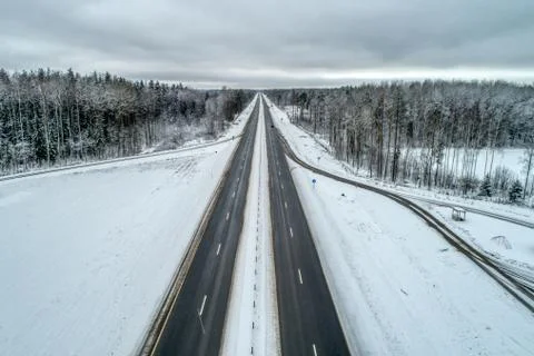 Freeway passing through the winter forest. The road goes away to the horizon Stock Photos