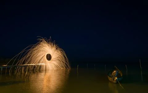 Freeze light using spinning burning steel wool  near an old boat on the lake Stock Photos