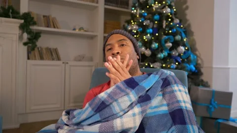 Freezing afro man rubbing hands because of cold in a blanket freezing indoors Stock Footage 223267500